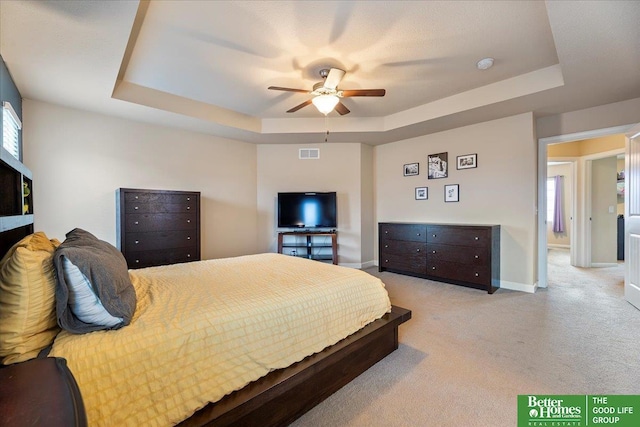 bedroom featuring a raised ceiling, ceiling fan, and light colored carpet