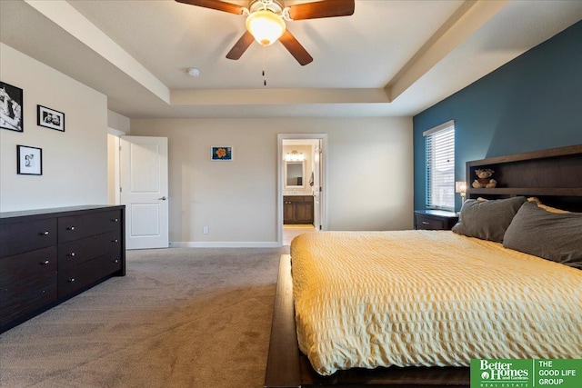 carpeted bedroom with ceiling fan, a raised ceiling, and ensuite bath