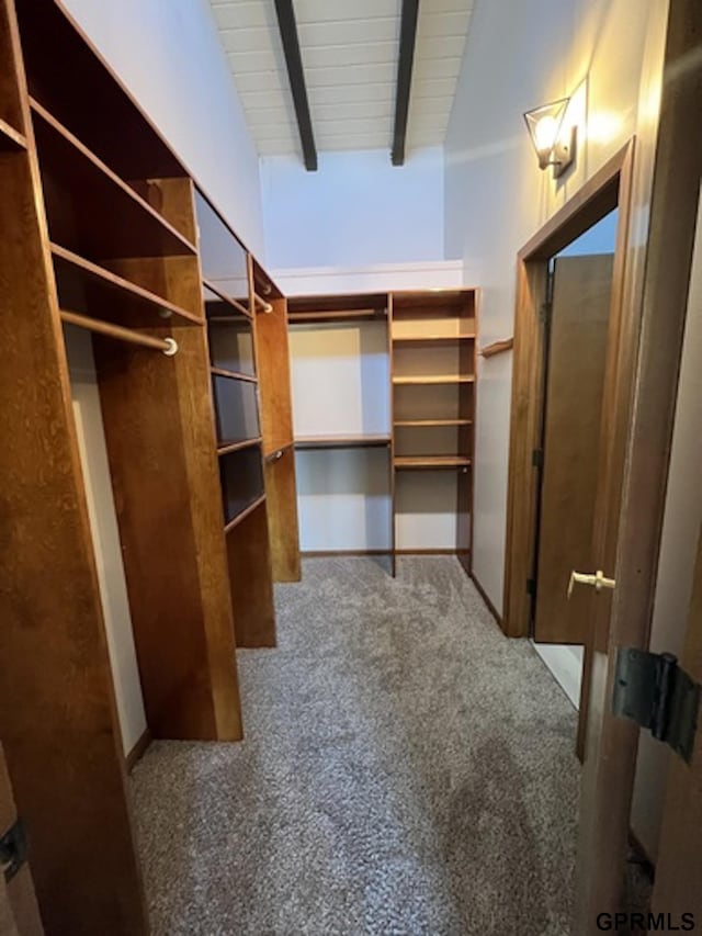 walk in closet featuring carpet and lofted ceiling with beams