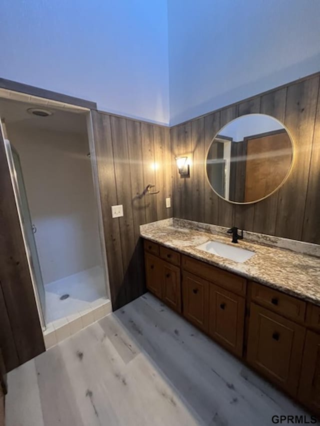 bathroom with a shower, vanity, hardwood / wood-style flooring, and wooden walls