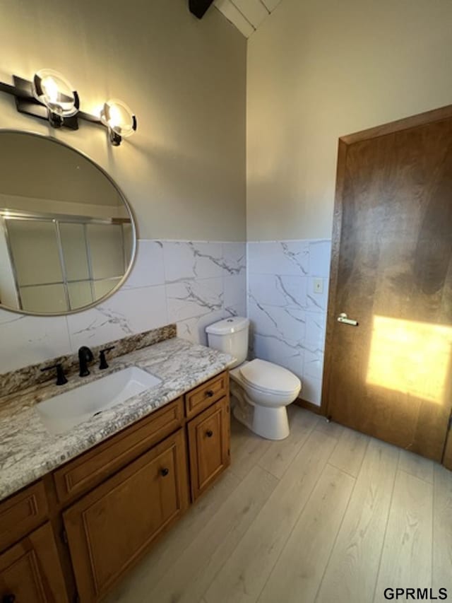 bathroom with vanity, toilet, wood-type flooring, and tile walls