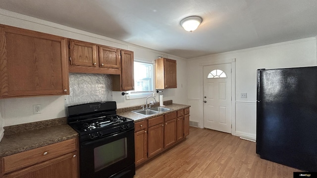 kitchen featuring sink, light hardwood / wood-style floors, decorative backsplash, black appliances, and ornamental molding