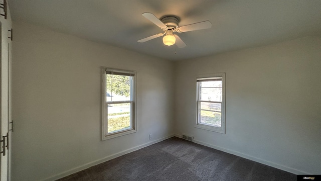 spare room featuring dark carpet and ceiling fan