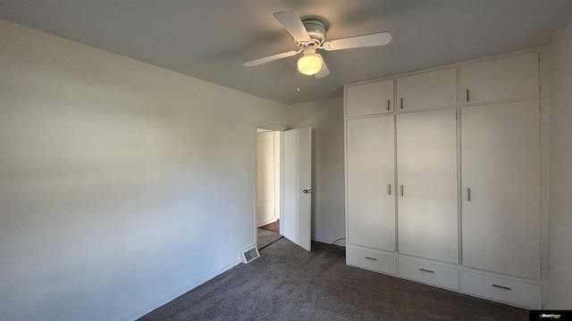 unfurnished bedroom featuring ceiling fan, dark carpet, and a closet