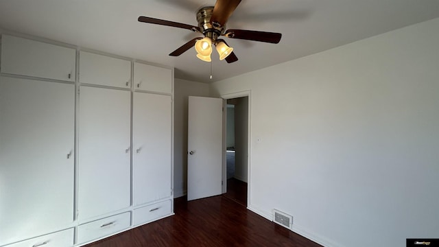 unfurnished bedroom with dark hardwood / wood-style flooring, a closet, and ceiling fan