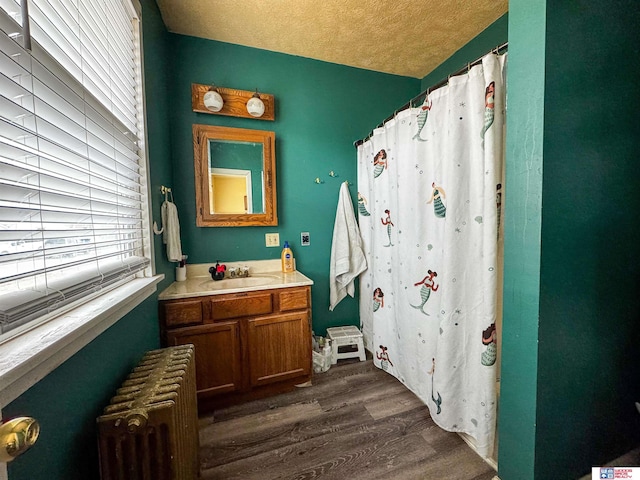 bathroom featuring radiator, walk in shower, a textured ceiling, vanity, and hardwood / wood-style flooring