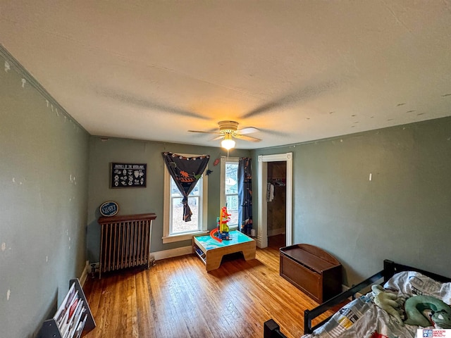 recreation room featuring radiator, ceiling fan, and hardwood / wood-style flooring