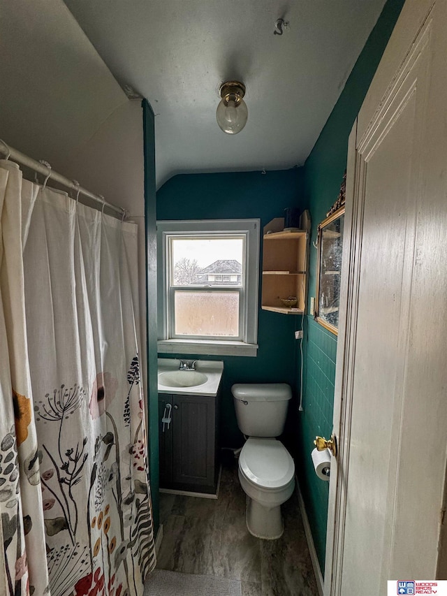 bathroom featuring a shower with shower curtain, vanity, toilet, and vaulted ceiling