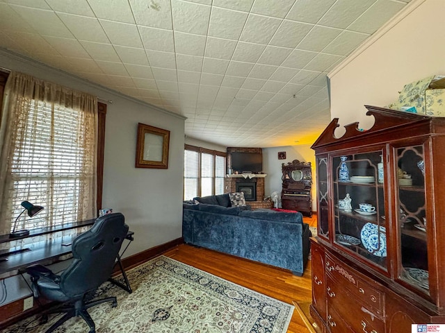 living room with dark hardwood / wood-style flooring, ornamental molding, a wealth of natural light, and a brick fireplace