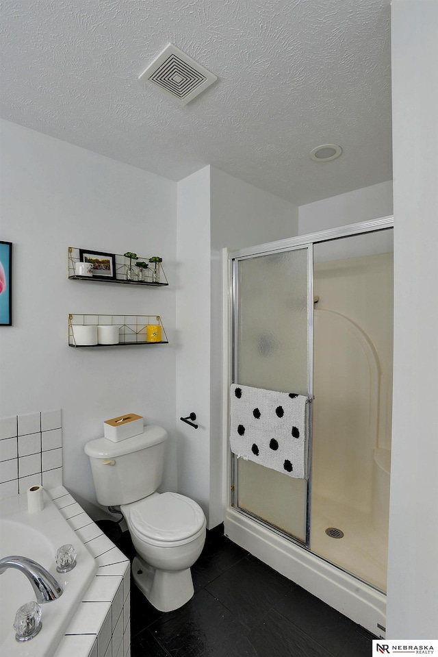 bathroom featuring tile patterned floors, shower with separate bathtub, toilet, and a textured ceiling