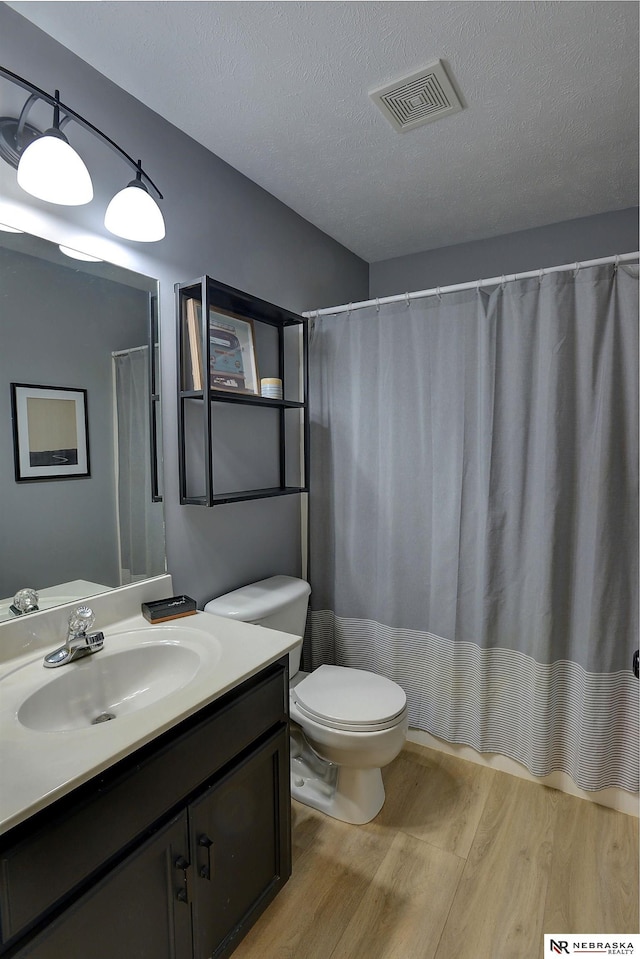 bathroom featuring toilet, vanity, a textured ceiling, and hardwood / wood-style flooring