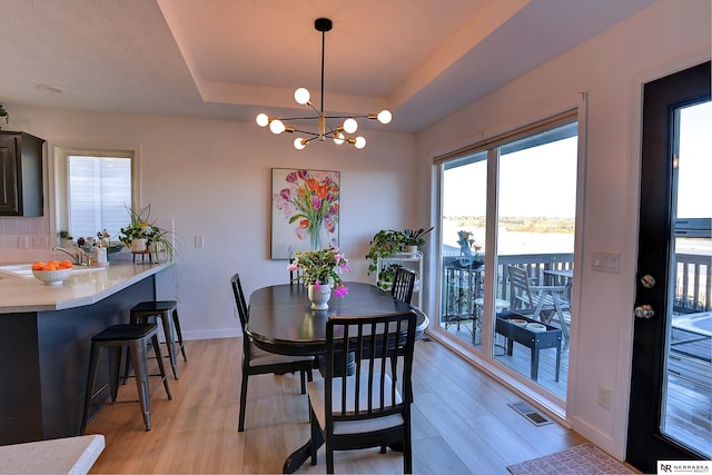 dining area with a chandelier, light hardwood / wood-style flooring, a healthy amount of sunlight, and sink