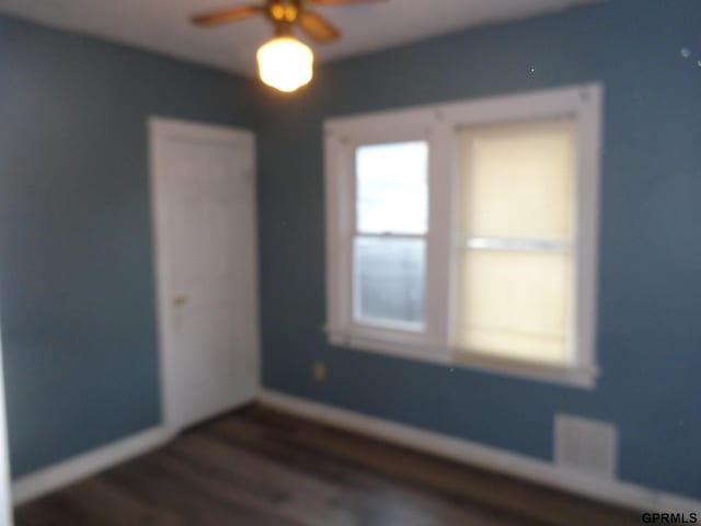 unfurnished room featuring ceiling fan and dark wood-type flooring