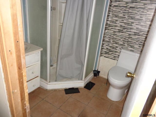 bathroom with tile patterned flooring, toilet, a shower, and vanity