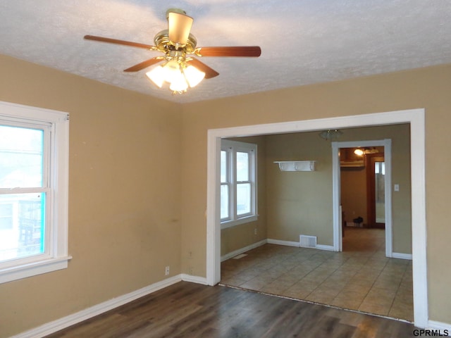 spare room featuring dark hardwood / wood-style floors, ceiling fan, and a textured ceiling