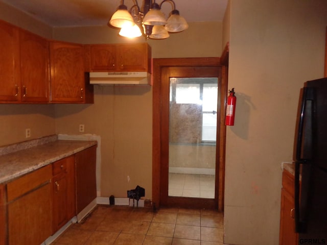 kitchen with black refrigerator, light tile patterned floors, decorative light fixtures, and an inviting chandelier