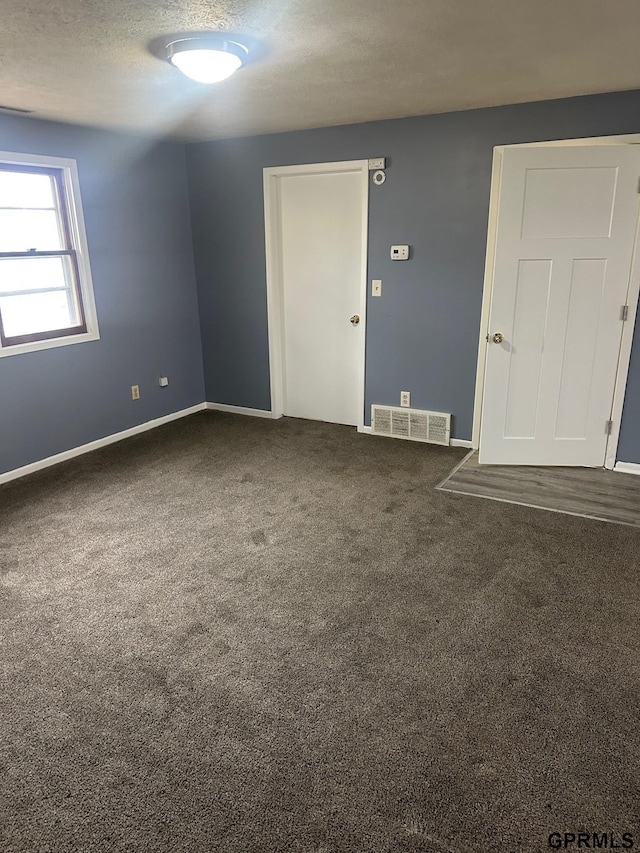 carpeted empty room featuring a textured ceiling