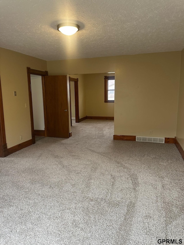 carpeted empty room featuring a textured ceiling