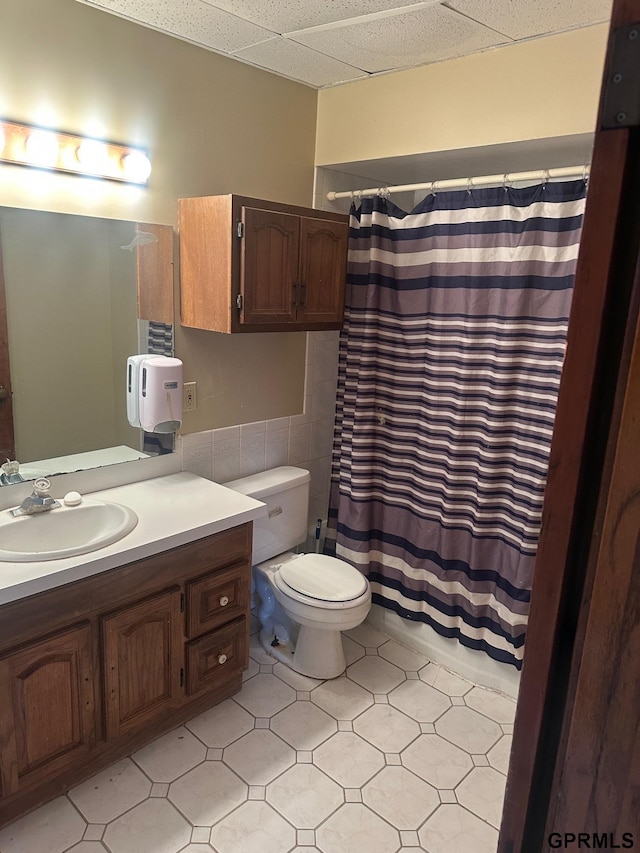 bathroom featuring vanity, a drop ceiling, tile patterned floors, toilet, and walk in shower