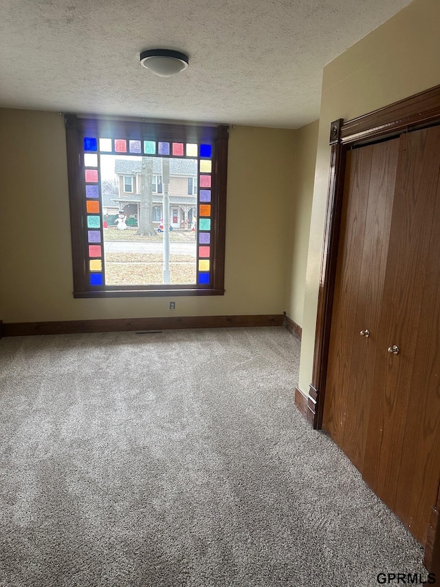 carpeted spare room featuring a textured ceiling