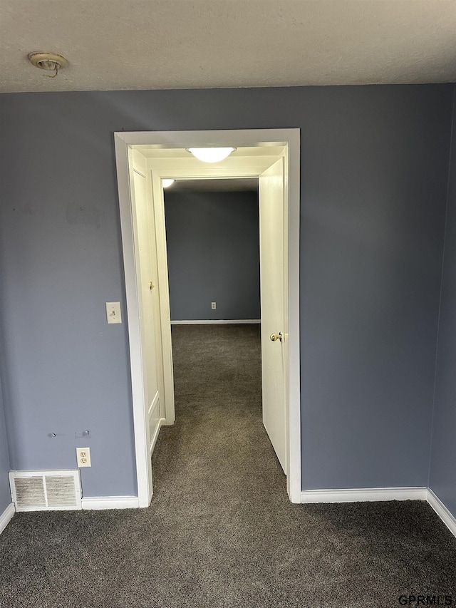 hallway featuring dark colored carpet