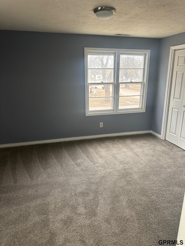 carpeted spare room featuring a textured ceiling