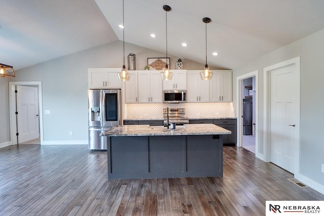 kitchen with a center island with sink, white cabinets, lofted ceiling, and appliances with stainless steel finishes