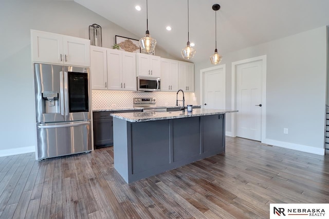 kitchen with white cabinets, stainless steel appliances, light hardwood / wood-style flooring, and a kitchen island with sink