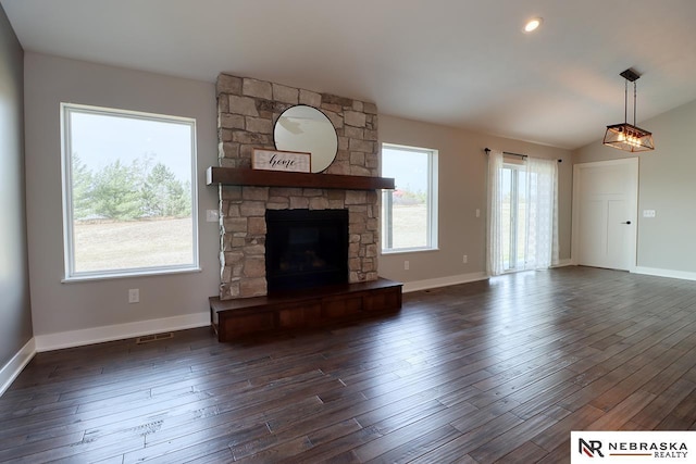 unfurnished living room featuring a stone fireplace and dark hardwood / wood-style flooring