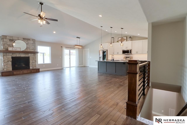 kitchen featuring white cabinetry, stainless steel appliances, dark hardwood / wood-style floors, lofted ceiling, and a center island with sink