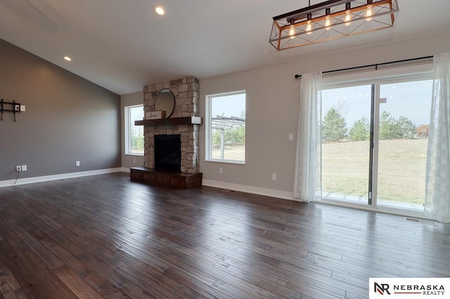 unfurnished living room with a stone fireplace, plenty of natural light, dark wood-type flooring, and lofted ceiling