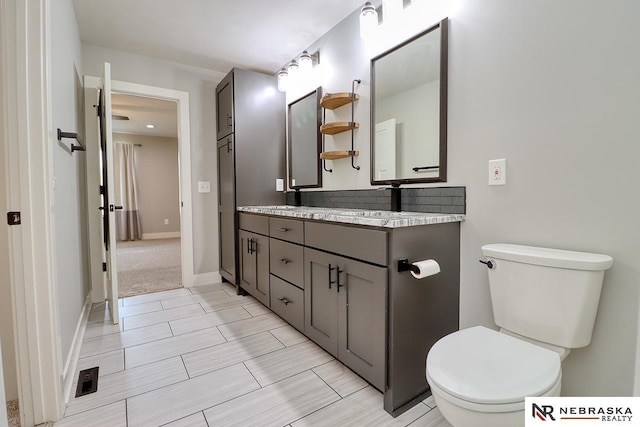 bathroom featuring vanity, toilet, and decorative backsplash