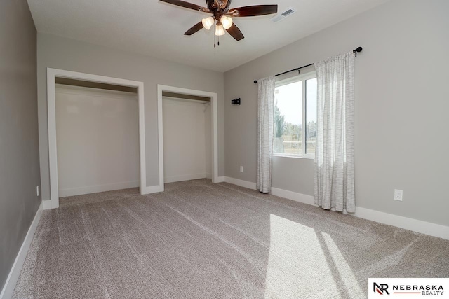 unfurnished bedroom featuring multiple closets, ceiling fan, and carpet floors