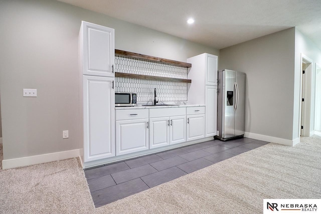 kitchen with carpet, white cabinets, sink, and stainless steel appliances