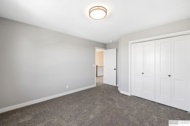 unfurnished bedroom featuring dark carpet and a closet