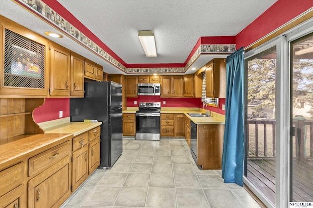 kitchen with a textured ceiling, sink, light tile patterned floors, and black appliances