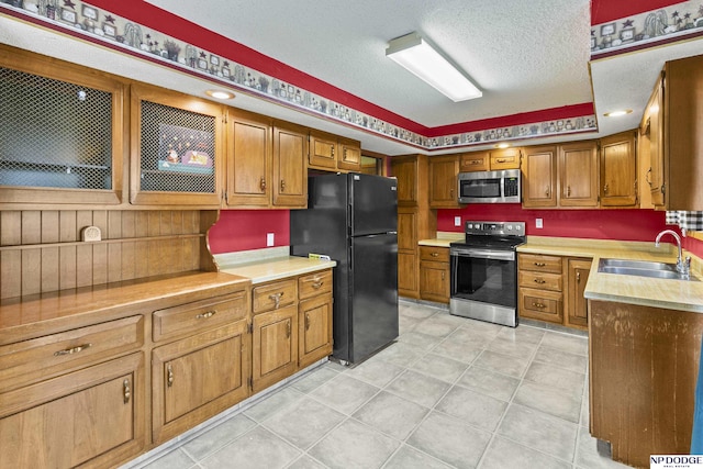 kitchen with sink, light tile patterned flooring, stainless steel appliances, and a textured ceiling