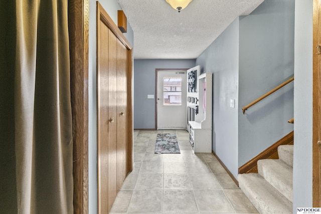 hallway with light tile patterned flooring and a textured ceiling