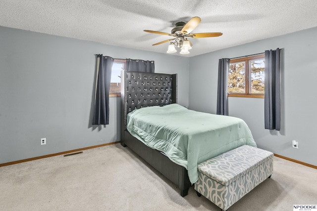 bedroom with light carpet, a textured ceiling, and ceiling fan