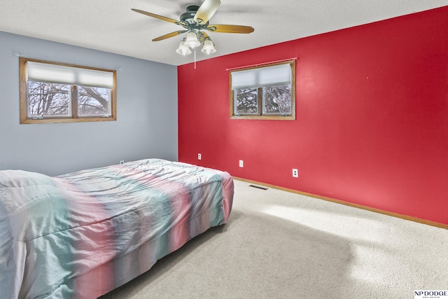 bedroom featuring ceiling fan, light colored carpet, and a textured ceiling