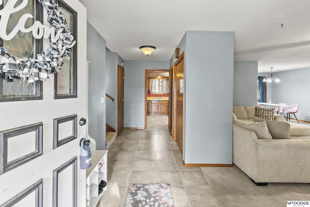 tiled foyer entrance with a textured ceiling and an inviting chandelier