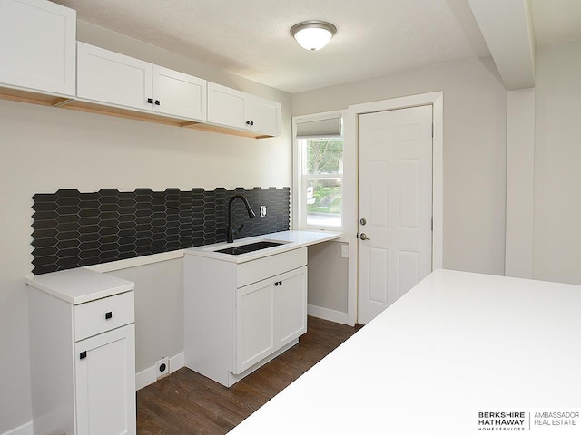 kitchen featuring backsplash, dark hardwood / wood-style flooring, sink, and white cabinets