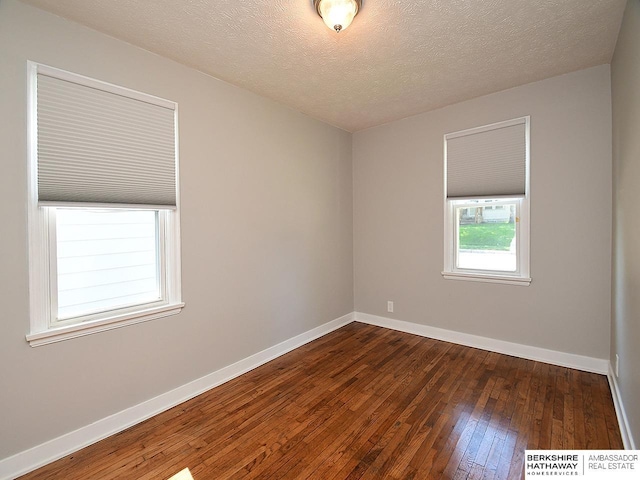 unfurnished room featuring a textured ceiling and dark hardwood / wood-style floors