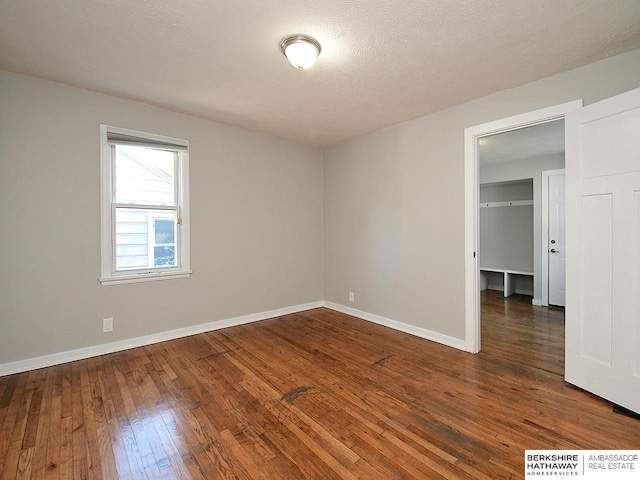 empty room with a textured ceiling and dark hardwood / wood-style floors