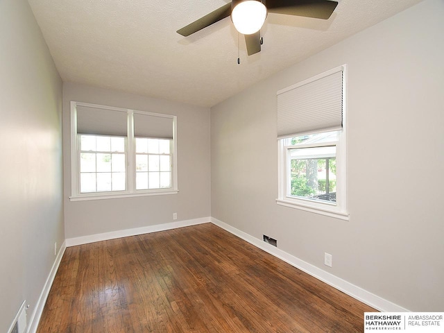 spare room with plenty of natural light, dark hardwood / wood-style floors, and a textured ceiling