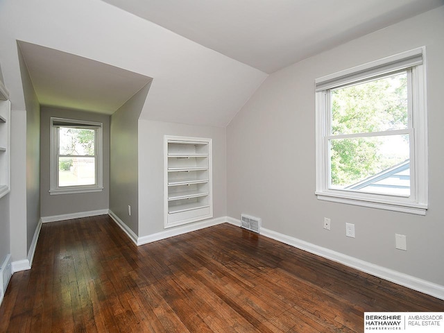 additional living space with built in shelves, lofted ceiling, and dark wood-type flooring