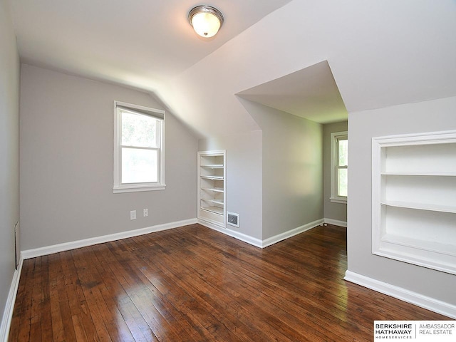 additional living space with built in shelves, dark hardwood / wood-style floors, and a wealth of natural light