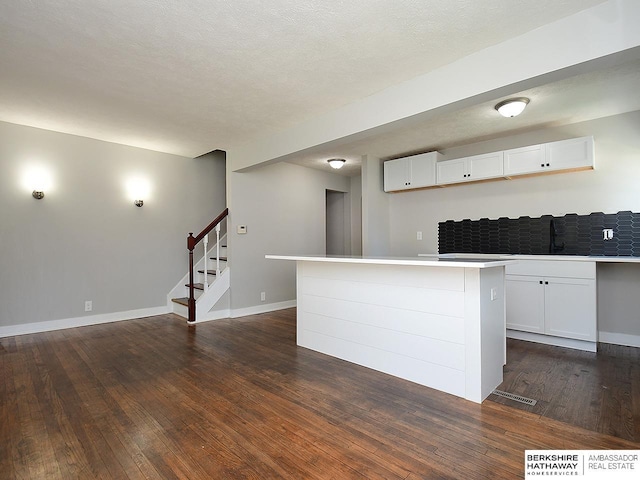 kitchen featuring a kitchen island, dark hardwood / wood-style flooring, white cabinetry, and a textured ceiling