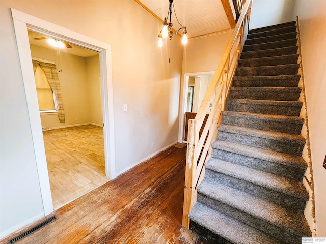 stairs featuring hardwood / wood-style flooring and an inviting chandelier