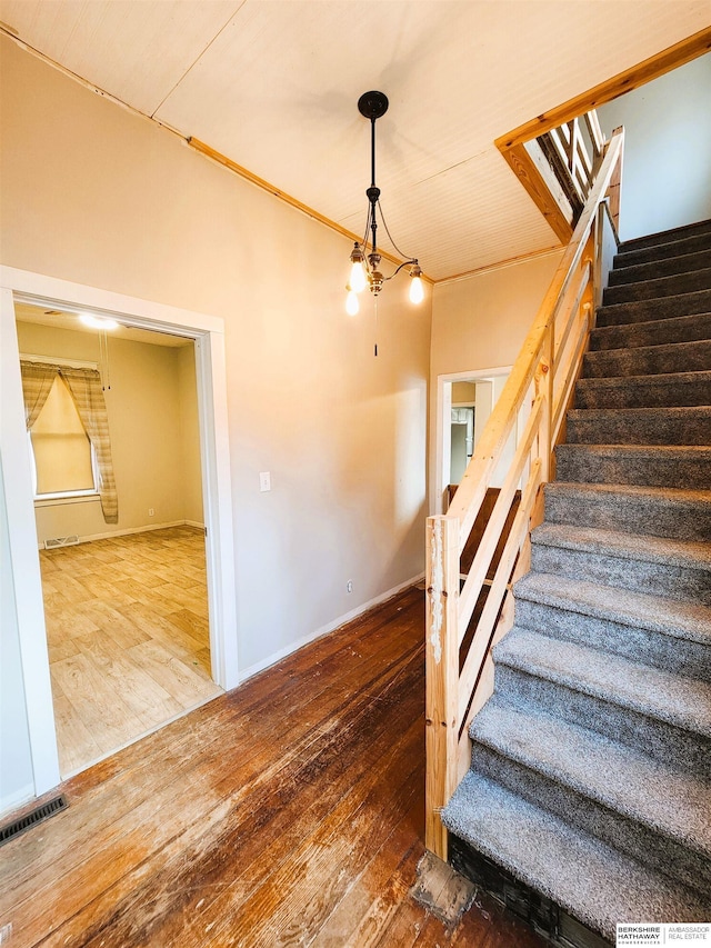 staircase with wood-type flooring and a chandelier